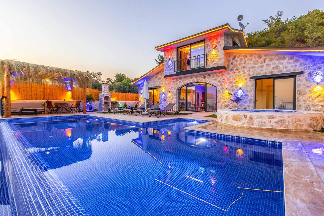 services-03 Elegant stone villa with illuminated facade, pool, and relaxing outdoor area.